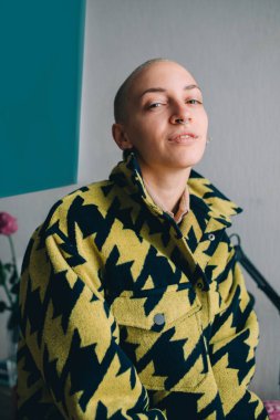 Kısa saçlı, şık bir ceket giyen ve kameraya poz veren bir kadın.