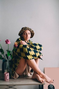 Masada oturan ve poz verirken kameraya bakan kadın.