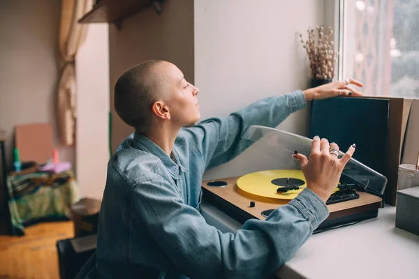 Žena sedí u svého vinylového hudebního přehrávače a připravuje se poslouchat hudbu — Stock fotografie
