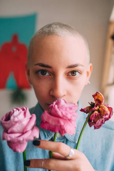 Mulher vestindo camisa jeans segurando flores secas e olhando para a câmera — Fotografia de Stock