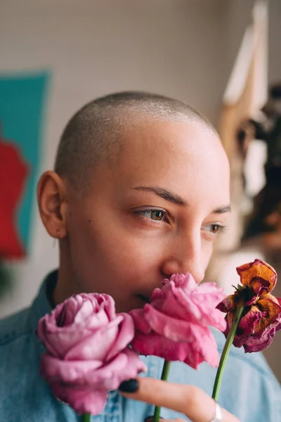 Donna con i capelli corti che tiene fiori secchi e guarda la finestra — Foto Stock