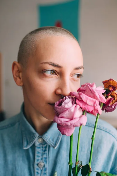 Donna con i capelli corti che tiene fiori secchi e guarda la finestra — Foto Stock