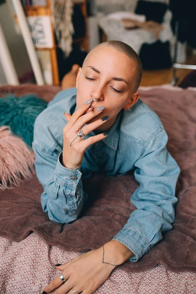 女人躺在床上时，用手吸着卷烟 — 图库照片