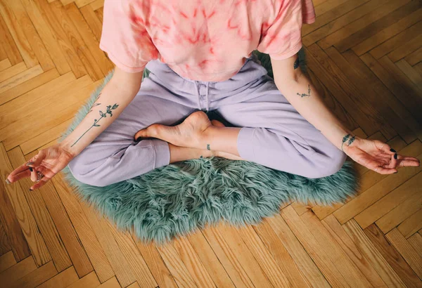 Mujer meditando en casa mientras está sentada en el suelo en pose de loto —  Fotos de Stock