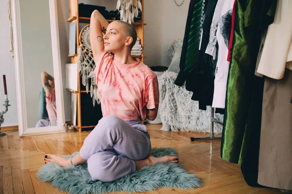 Жінка з коротким волоссям робить йогу на дерев'яній підлозі, сидячи у вітальні — стокове фото