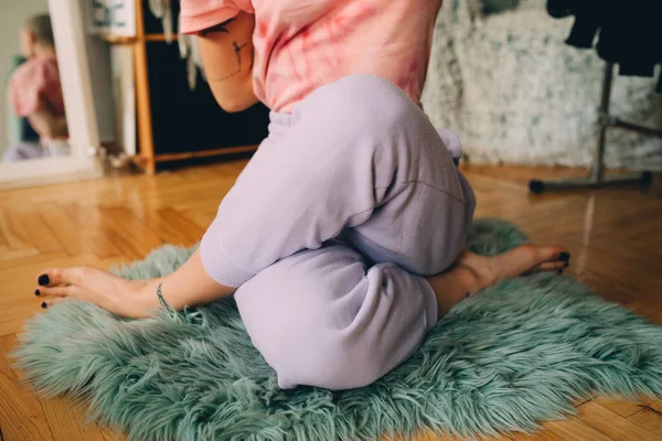 Vrouw in huiselijke kleding mediterend en yoga hebbend in haar gezellige woonkamer — Stockfoto