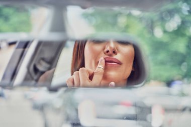 Arabadaki aynaya bakan kız.