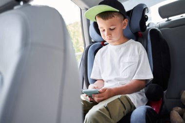 Çocuk arabayla yolculuk sırasında mobil oyunlar oynuyor