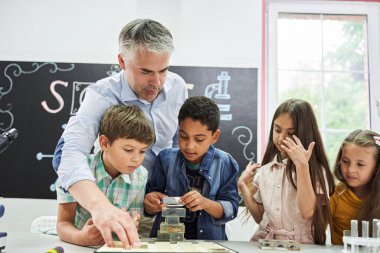 Çocuklar cam örneklerini böceklerle istifliyor.