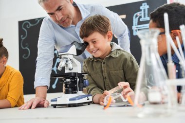 Yakışıklı, kıdemli, kır saçlı öğretmen ders çalışmaya yardım ediyor.