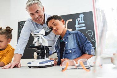 Yakışıklı, gri saçlı öğretmen çocuğa tatmin olmuş görünüyor.