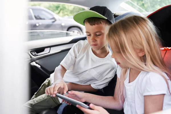 Симпатичные братья и сестры с помощью цифрового планшета в машине — стоковое фото