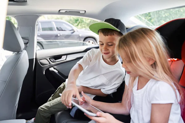 Heureux garçon et fille jouer sur tablette en voiture — Photo