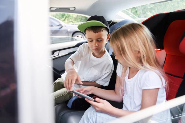 Feliz hermano y hermana jugando en la tableta en el coche — Foto de Stock