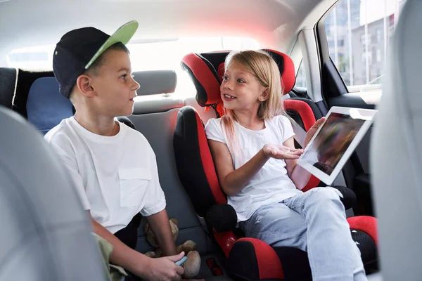 Vrolijke broers en zussen reizen in de auto met tablet — Stockfoto