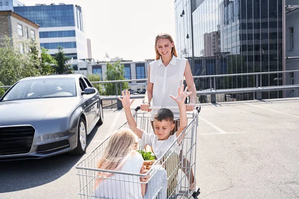 Весела молода жінка, що носить візок з дітьми — стокове фото