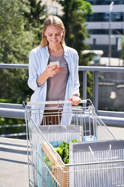 Mensajería mujer feliz en el teléfono inteligente durante las compras —  Fotos de Stock