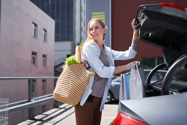 Mujer bonita sonriente con coche cerca del supermercado — Foto de Stock