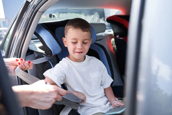 Vårdande mor fastsättning säkerhetsbälte för son — Stockfoto