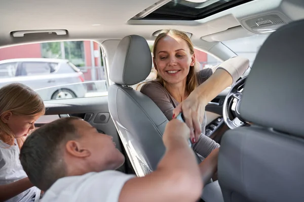 차에서 아이들에게 스마트폰을 주는 행복 한 여성 — 스톡 사진