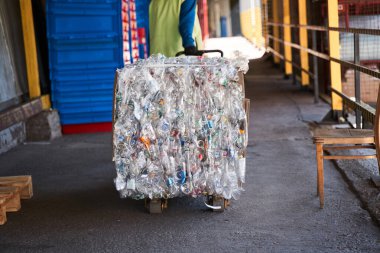 İşçi plastik şişeli bir araba taşıyor.