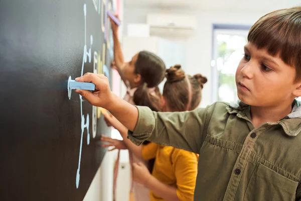 Carino scolaro scrittura su un lavagna in un aula — Foto Stock