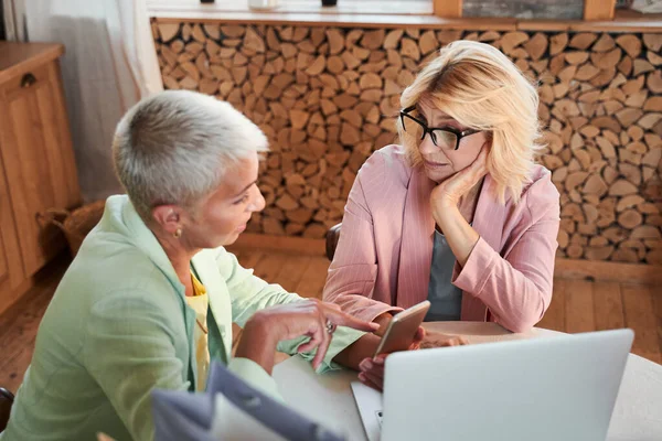 Lady visar något i telefonen till sin barndomsvän — Stockfoto