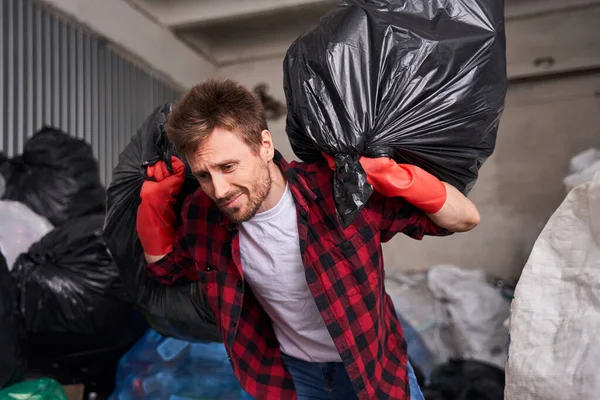 Man carrying heavy garbage bags