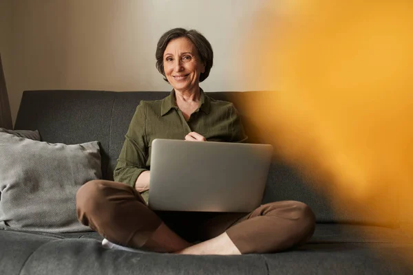 Woman sitting at the lotus pose and holding laptop at the knees while using Internet — стокове фото