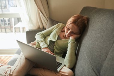 Uzaktan eğitim alırken bilgisayardan bir şey izleyen bir kız.