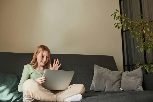 Happy small child sitting at the sofa while studying online — Photo