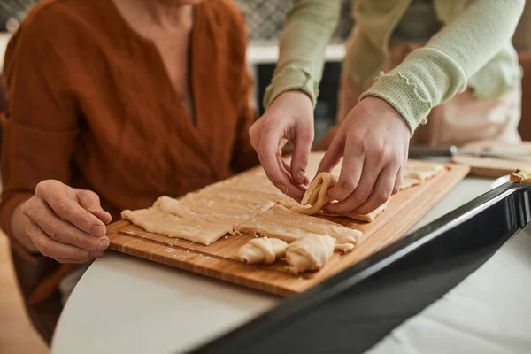 Girl preparing bagels from the dough while helping to her senior grandmother — Stock fotografie