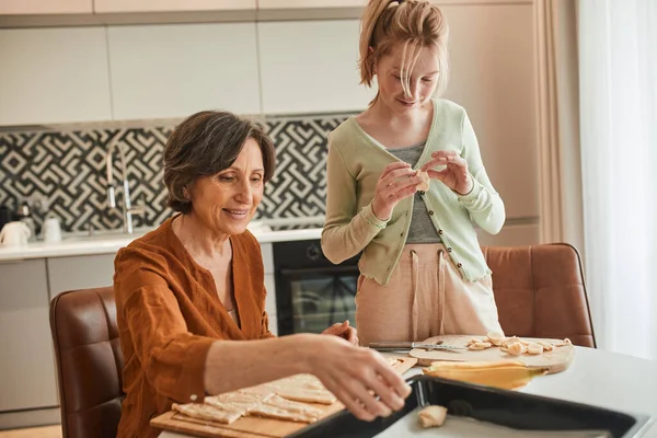 Abuela con su nieta cocina plato juntos, mientras que la preparación de panecillos frescos — Foto de Stock