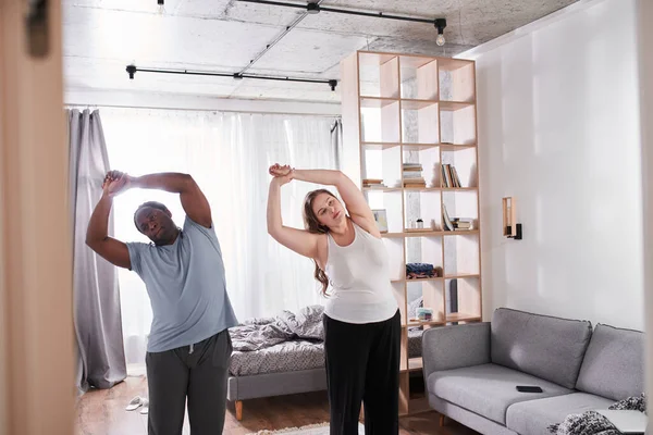 Positive nice diverse couple working out while doing sport together at home — Φωτογραφία Αρχείου