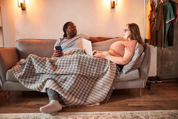 Casal sentado sob o cobertor e conversando enquanto passa o tempo preguiçoso — Fotografia de Stock