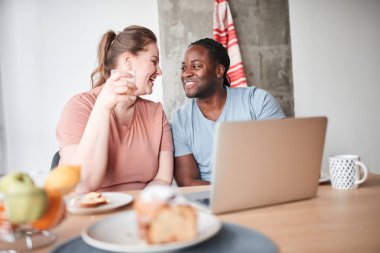 Çift birbirine şefkatle bakıyor ve kahvaltı ederken gülümsüyor.