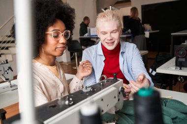 Tasarımcı yeni çizimler çiziyor ve çok ırklı meslektaşına bir şeyler anlatıyor.