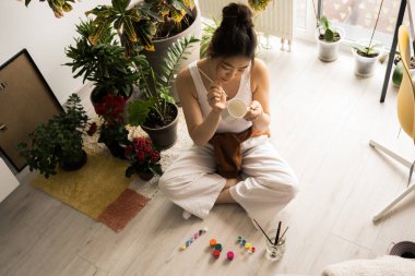 Oturma odasında resim yapan kadın ressam, yerde oturup resim çiziyor.