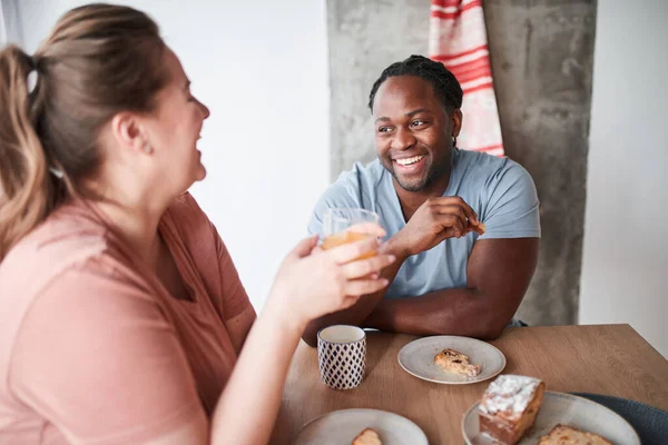 Egy pár együtt reggelizik, miközben egymásra néznek és nevetnek. — Stock Fotó