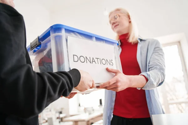 Albino man taking box from the client with second-rate clothing for the recycling — Stock Photo, Image