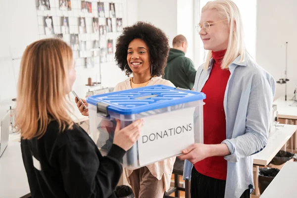 Man and female colleague taking box from the client with second-rate clothing — Stock Photo, Image