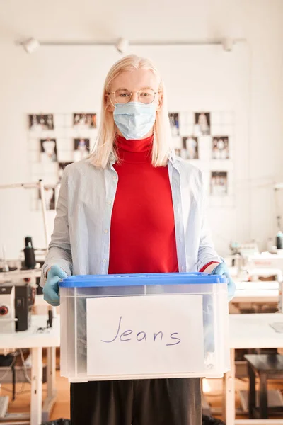 服を仕分け、ジーンズの服でプラスチック容器を保持して働く男 — ストック写真