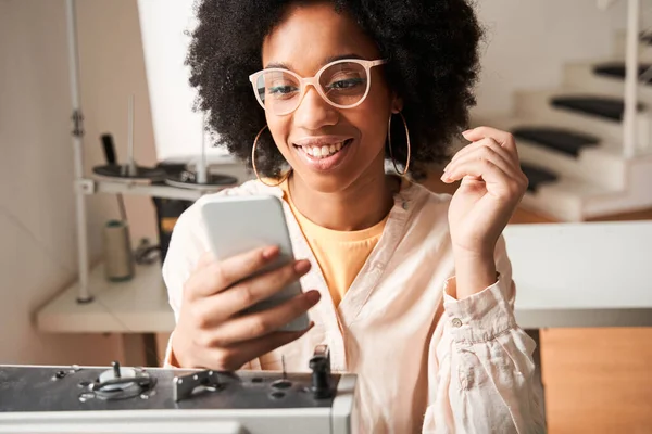 Woman wearing glasses checking messages at her smartphone with pleasure smile — Stockfoto