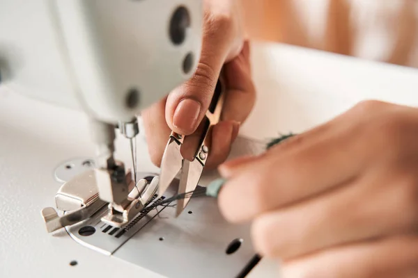 Woman cutting threads with scissors while finished re sewing clothes — Photo