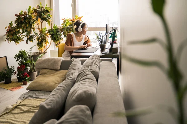 Žena s sluchátky pozorným pohledem na monitor při práci — Stock fotografie