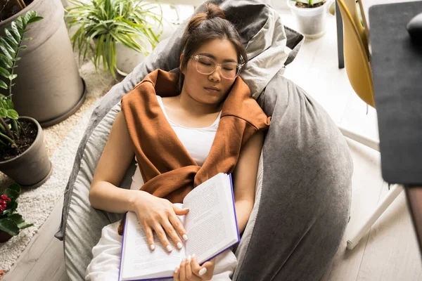 Calma mujer asiática durmiendo en la silla bolsa durante el libro de lectura —  Fotos de Stock