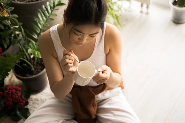 Female artist painting in her living room, while sitting at the floor and drawing — Stock Photo, Image