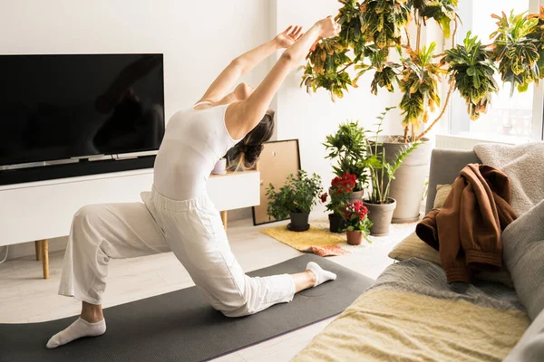 Woman wearing homewear practicing yoga in warrior pose at the light living room — Φωτογραφία Αρχείου