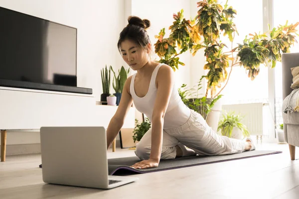 Multiracial woman stretching her legs while sitting on the mat — Φωτογραφία Αρχείου