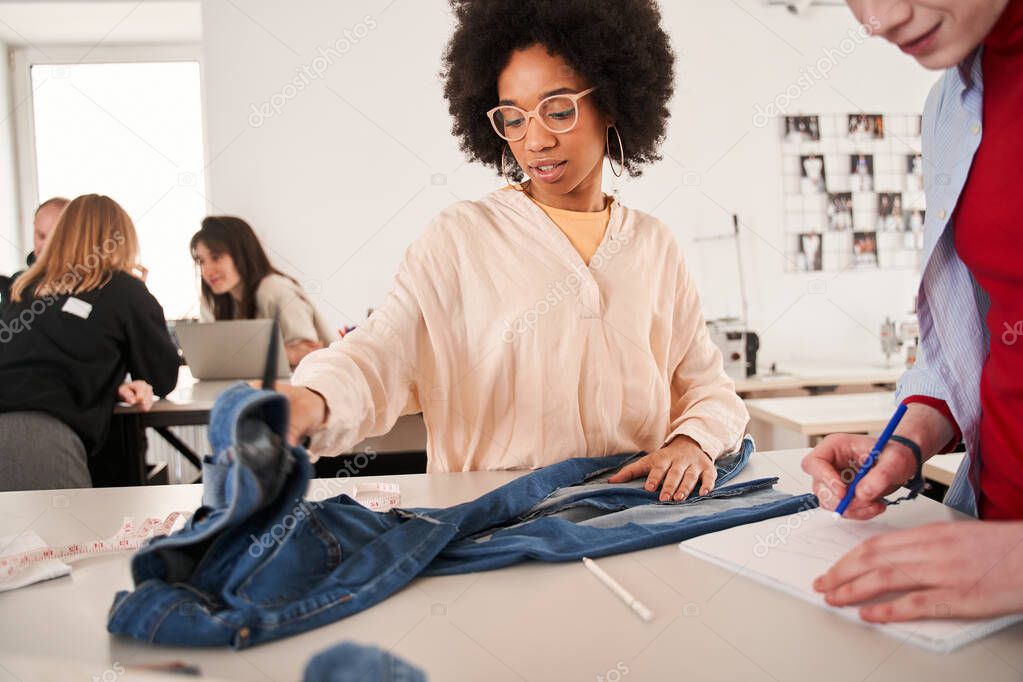 Woman discussing process of re sewing with her albino colleague while working